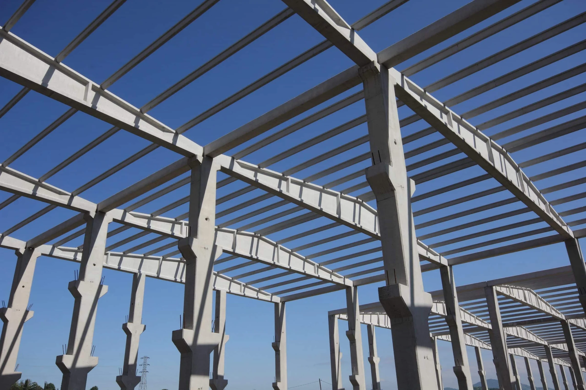 Galpão pré-fabricado em montagem: pilares, vigas de cobertura e terças de concreto